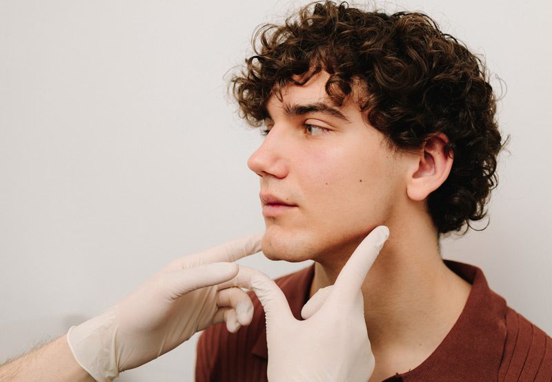 Doctor-palpating-male-patient's-neck