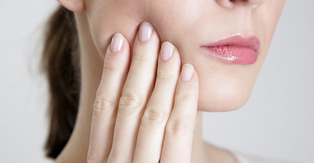 Woman-touching-fingers-to-side-of-jaw