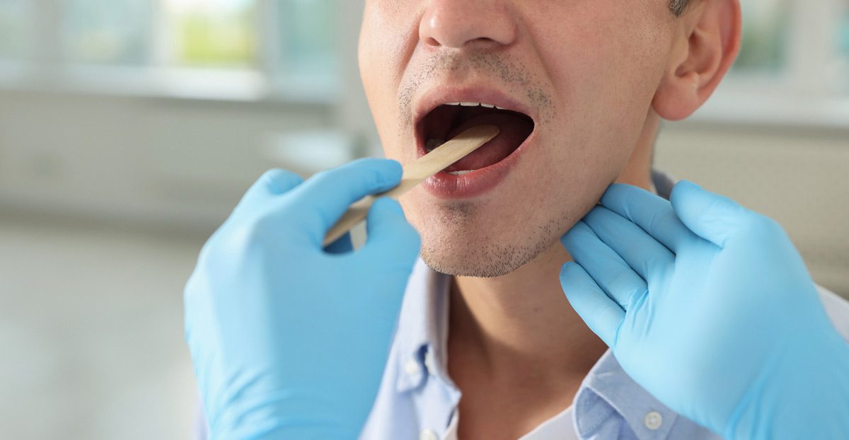 doctor-checking-mouth-of-patient-with-tongue-depressor